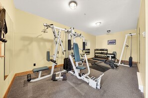 A gym with exercise equipment, a bench, and a wall-mounted dumbbell rack. - Fully Renovated Penthouse Loft w/ Bike Storage and Central Air Conditioning (Fernie)