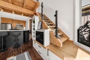 Una cocina moderna con vigas de madera, estufa empotrada y una zona de bar con taburetes.