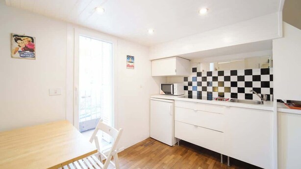 A compact kitchen with a microwave, a sink, and a checkered backsplash.