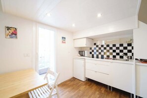 A compact kitchen with a microwave, a sink, and a checkered backsplash.
