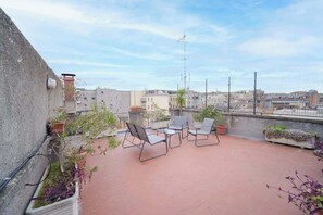 A rooftop terrace with outdoor seating, potted plants, and a view of the cityscape. - BuddyRent - Terrazza - Monti - 4 ospiti (Roma)