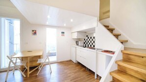 A modern kitchen with white cabinets, a wooden staircase, and a dining area with a table and chairs.