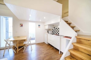 A modern kitchen with white cabinets, a wooden staircase, and a dining area with a table and chairs.
