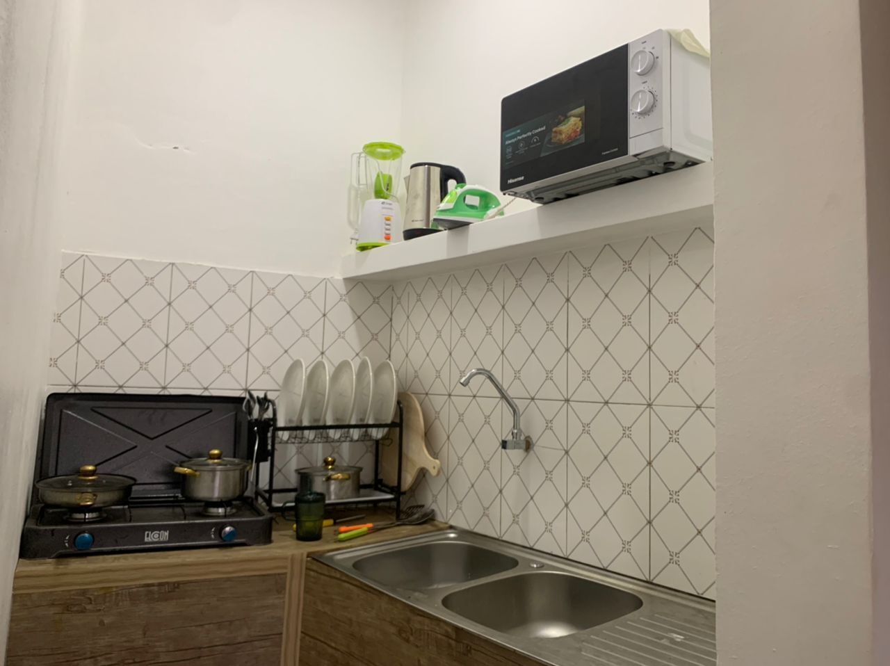 Une cuisine de taille réduite équipée d’une cuisinière à gaz, d’un four à micro-ondes et d’un évier.