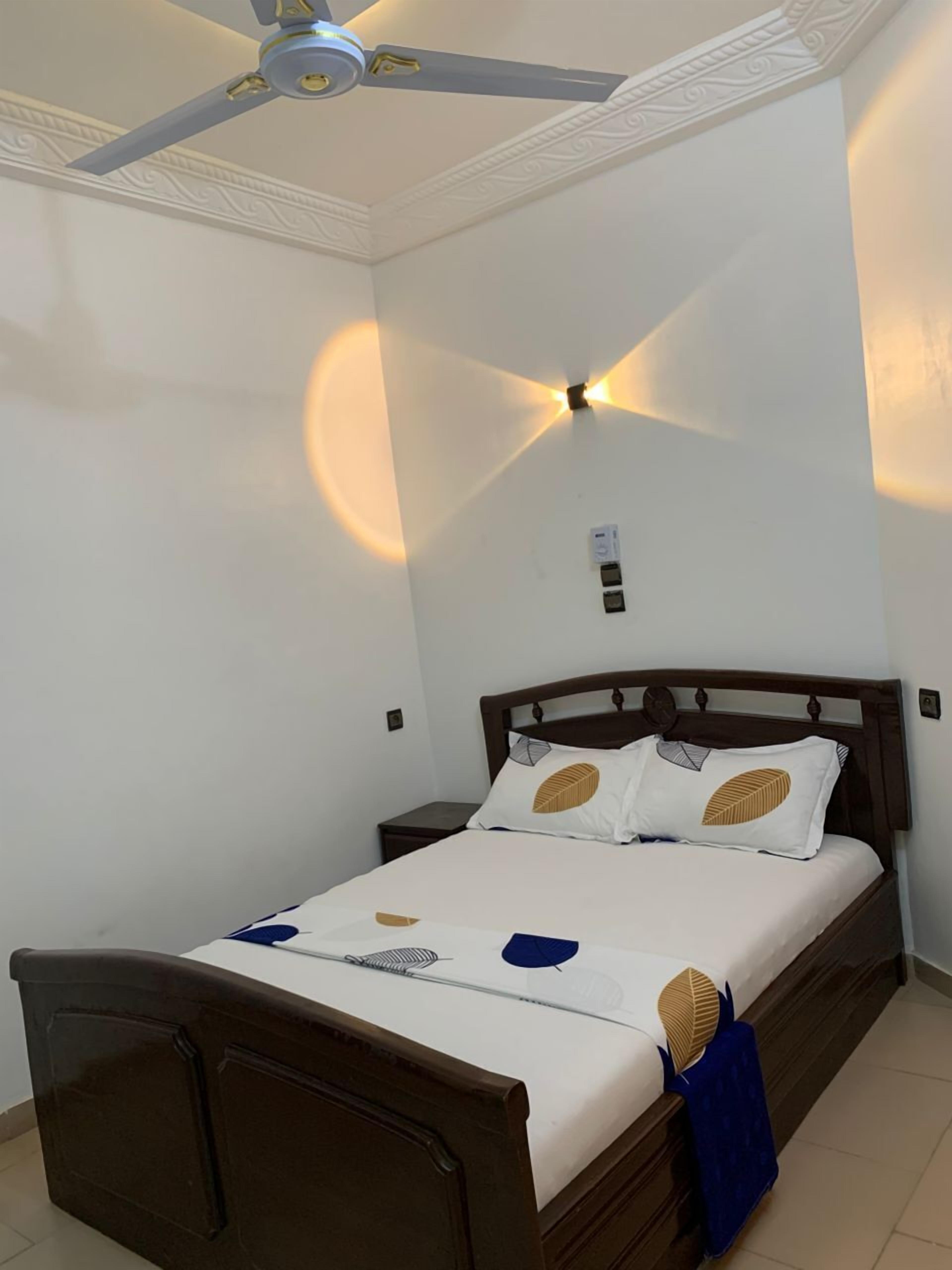 Une chambre à coucher avec un lit, un ventilateur de plafond et un luminaire fixé au mur.