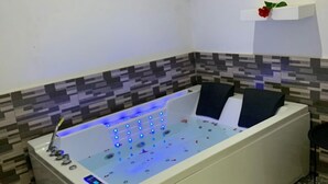 A modern bathroom with a freestanding bathtub, a digital control panel, and a decorative shelf with a rose.