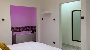 A modern bedroom with a large bed, a built-in vanity, and a bathroom visible through an open door.