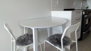 Une cuisine moderne avec des meubles blancs, une table ronde blanche et deux chaises dotées de coussins gris moelleux.
