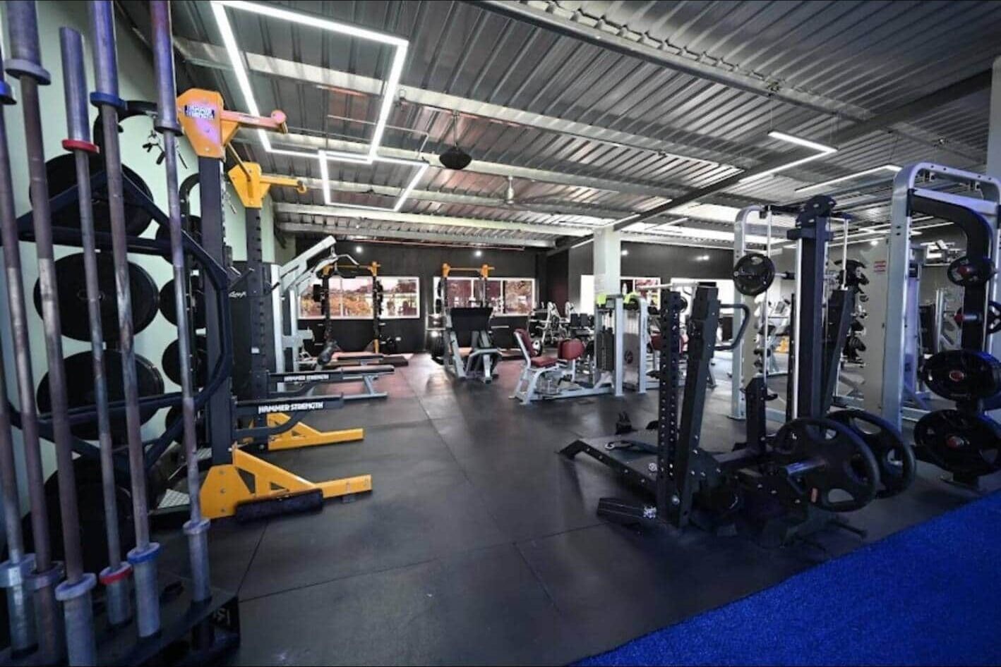 A gym with various weightlifting equipment, including benches and squat racks.