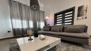 Un salon moderne avec un canapé, une table basse, une lampe et une plante.