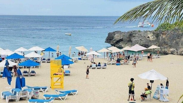 Une plage avec des parasols, des chaises longues et un poste de surveillance pour les sauveteurs.