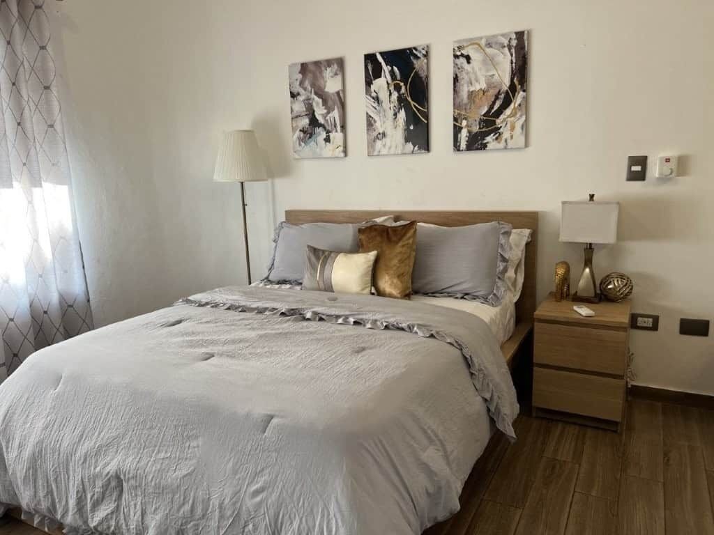 Una camera da letto con un letto grande, un comodino, una lampada e arte astratta alle pareti.