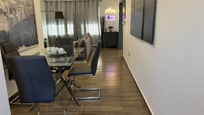 Un salon moderne avec un coin repas, un plancher en bois et une vue sur la ville.