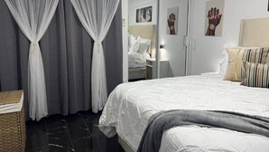 Une chambre à coucher avec un lit, des rideaux, une table de chevet et un miroir.