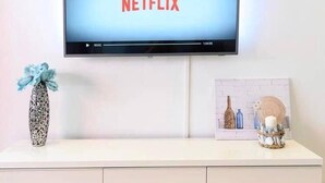 Televisor de pantalla plana montado en una pared blanca mostrando el logotipo de Netflix.