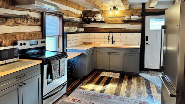Una cocina con vigas de madera, un refrigerador de acero inoxidable, un microondas y una estufa.