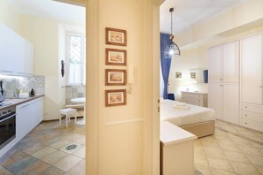 A modern kitchen with a dining area, a bedroom with a large bed and wardrobe, and a bathroom with a shower.