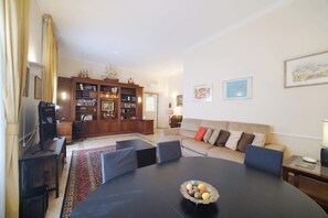 A living room with a round table, a sofa, a bookshelf, and a television.