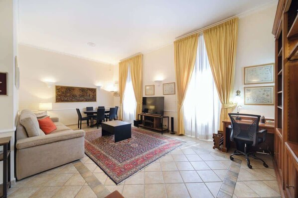Una sala de estar con sofá, mesa de centro, televisor, mesa de comedor, sillas y alfombra.
