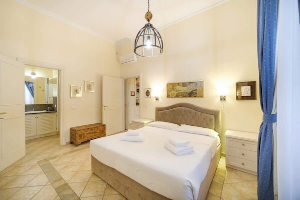 A bedroom with a bed, bedside tables, a wardrobe, and a mirror.