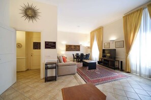 A living room with a sofa, coffee table, TV, and a patterned rug.