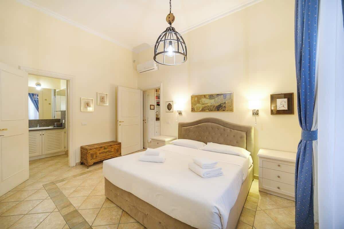 Une chambre à coucher avec un lit, des tables de chevet, une armoire et un miroir.