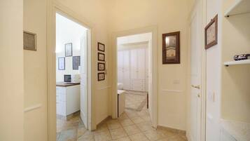 Un pasillo que conduce a una cocina y un baño con muebles y pisos de baldosas blancos.