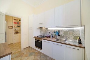 A kitchen with white cabinets, a stove, a sink, and a tiled backsplash.