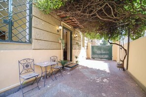 A courtyard with a covered seating area, a door, and a green gate.