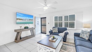 A modern living room with a large flat-screen TV, a wooden console table, a blue sofa, and a coffee table. - Sunset Beachfront Bliss
Wake Up to Waves & Gulf Views!
New heated Pool! (Treasure Island)