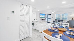 A modern kitchen with white cabinetry, a dining area with blue placemats, and a view of the ocean through large windows. - Sunset Beachfront Bliss
Wake Up to Waves & Gulf Views!
New heated Pool! (Treasure Island)
