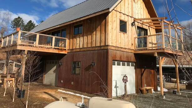 A wooden two-story house with a metal roof, a balcony, and a garage. - A Restful Retreat Just A Stones Throw Away From Downtown  (Quincy)