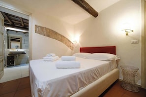 Una camera da letto con un letto, una testiera rossa, un comodino e un punto luce a parete.