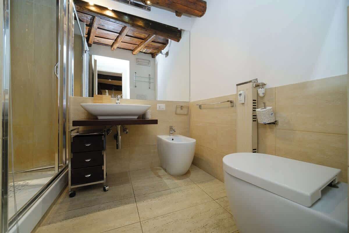A bathroom with a bidet, toilet, and a sink with a cart.