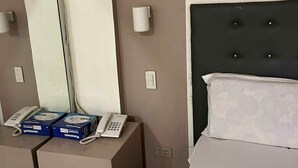 Ένα δωμάτιο ξενοδοχείου με ένα κρεβάτι, έναν μεγάλο καθρέφτη, δύο τηλέφωνα στα κομοδίνα και ένα μικρό τραπέζι με κουτιά.