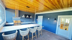 Una cocina moderna con techo de madera, una isla integrada con taburetes y vistas al área de comedor contigua.