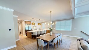 Una cocina moderna con una isla central, iluminación colgante y un comedor con alfombra.