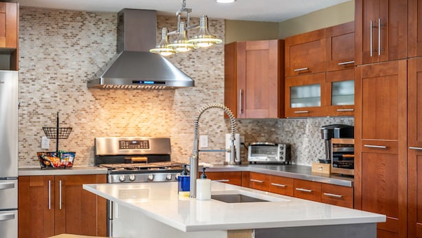 Une cuisine moderne avec des meubles en bois, une cuisinière en acier inoxydable et un îlot central doté d’un évier.