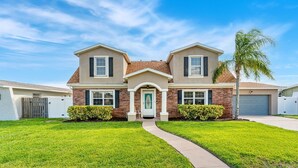 Une maison à deux étages, avec une entrée à l’avant, une allée et une pelouse bien entretenue.