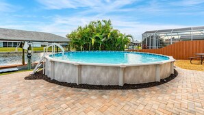 Une piscine dotée d’une terrasse en bois, entourée de palmiers et délimitée par une clôture en bois.