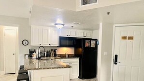 A kitchen with white cabinets, a black refrigerator, and a granite countertop. - SeaWorld Orlando | 2BR | Minutes to the Parks (Orange County)