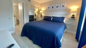 A bedroom with a large bed, bedside lamps, a mirror, and framed pictures on the wall. - SeaWorld Orlando | 2BR | Minutes to the Parks (Orange County)