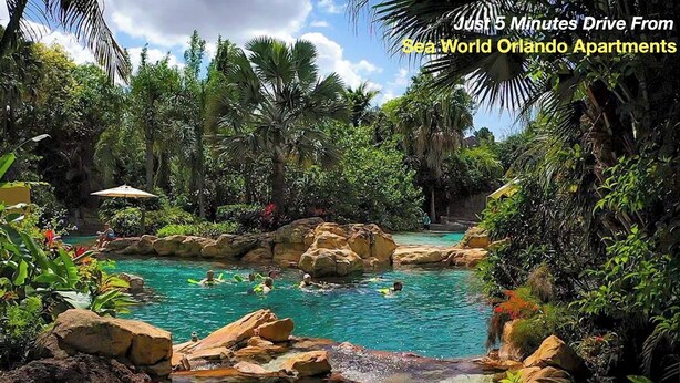 A tropical pool surrounded by lush greenery and rocks. - SeaWorld Orlando | 2BR | Minutes to the Parks (Orange County)