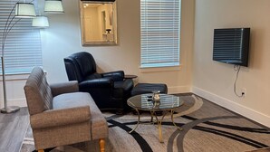 Un salon comprenant un canapé, une table basse, un ventilateur de plafond et un téléviseur.