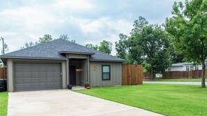 Une maison de plain-pied avec un garage, une pelouse devant et une clôture en bois.
