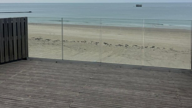 Um deck de madeira com vista para uma praia e oceano.
