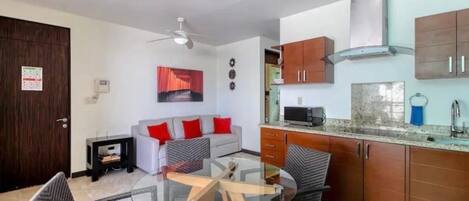Une cuisine moderne équipée d’un four à micro-ondes, d’une cuisinière et de placards. On y trouve également un coin repas avec une table et des chaises en verre.
