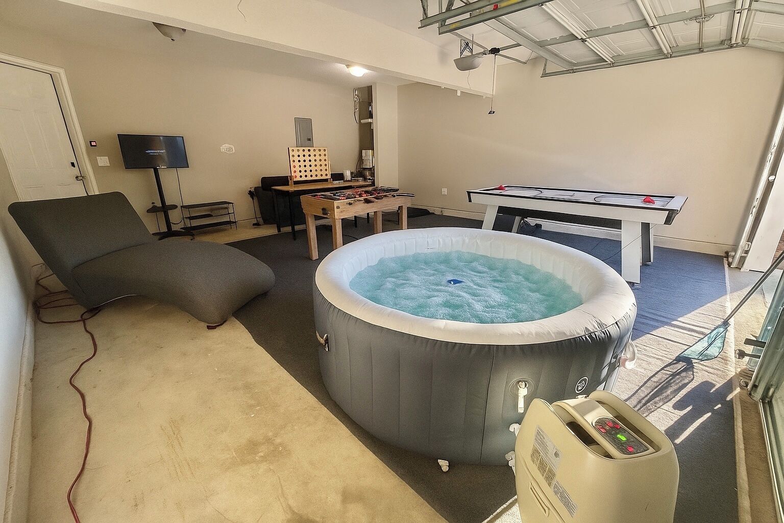 Une pièce équipée d’un jacuzzi, d’une table de billard, d’un fauteuil et d’un téléviseur.