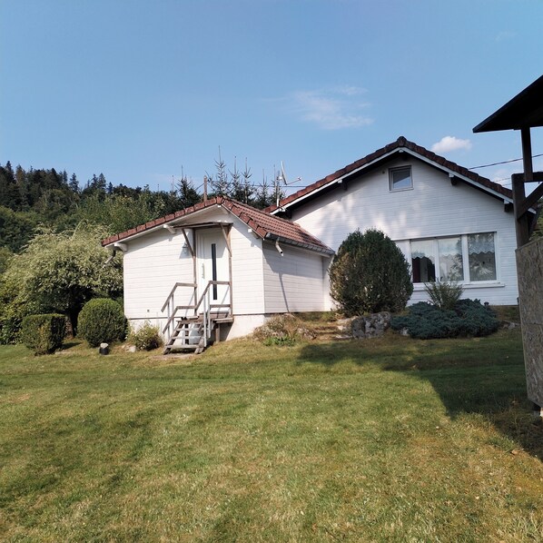 Ein eingeschossiges Haus mit Satteldach, einer Veranda und einer kleinen angebauten Garage.