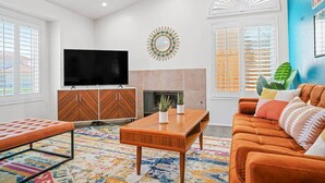 Un salon comprenant un téléviseur, un canapé, une table basse et un tapis à motifs.